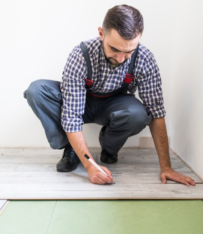 Professionnel traçant une lame de parquet avant la découpe et la pose au sol.